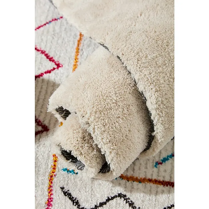 Alfombra de pelo corto Toscana - Blanco, 230 x 160 cm, 100% Poliéster - Primer plano de una alfombra bereber enrollada con estampados geométricos coloridos, que destaca la textura suave.
