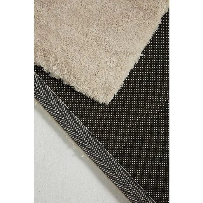 Alfombra de pelo corto Toscana - Blanco, 230 x 160 cm, 100% Poliéster - Primer plano de una alfombra de pelo largo beige con un respaldo antideslizante y una cinta con estampado de espiga.