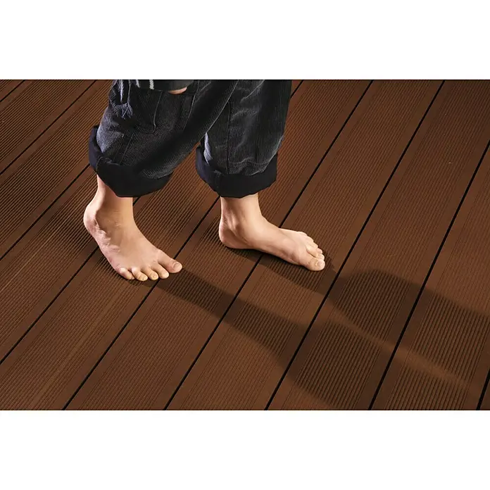 Kovalex WPC-Terrassenpaket Exklusiv - Braun, 4 x 4,95 m - Barfuß auf einer braunen Terrassendiele aus robustem WPC-Material. Ideal für den Außenbereich, langlebig und pflegeleicht.