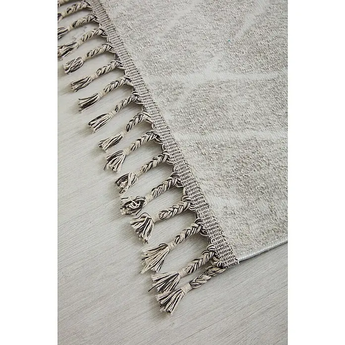 Alfombra de pelo corto Claudia Rombos - Crema, 60 x 110 cm, 100% poliéster - Primer plano de una alfombra gris con flecos trenzados y una textura sutil. Los flecos añaden un acento decorativo al diseño.