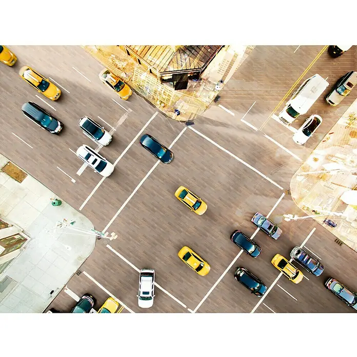 MyStyle MyDream Laminado Roble Bandito - 1.285 x 192 x 14 mm, Efecto madera campestre, AC5 - Vista aérea de una calle bulliciosa con coches aparcados y peatones, capturando la escena urbana y el movimiento de la ciudad.