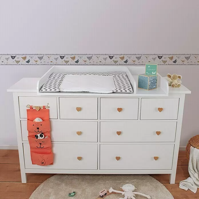 A.S. Création Lovely Kids Tapetenborte - Kunststoff, Hühner - Weißer Wickeltisch aus Holz mit Chevron-Wickelauflage, Herzgriffen und Hänge-Organizer in einem Kinderzimmer mit Bordüre und Spielzeug.