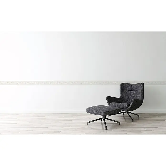 A.S. Création Only Borders 11 Tapetenborte - Weiß, 5 x 0,13 m, Strukturprofil - Moderner Sessel mit Fußhocker vor einer weißen Wand. Der Sessel ist dunkelgrau und hat ein minimalistisches Design.