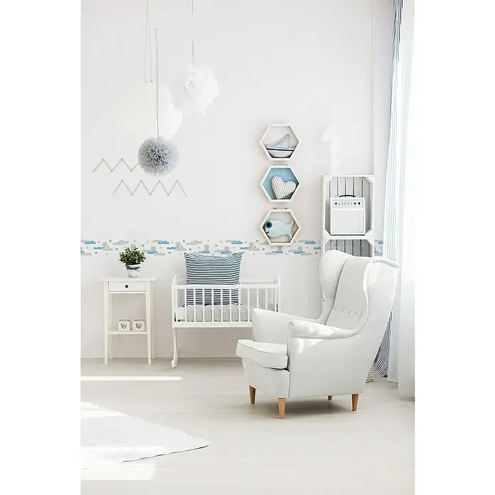 A.S. Création Lovely Kids Tapetenborte - Kunststoff, Wolke & Bär - Ein helles, kinderfreundliches Zimmer mit weißen Möbeln, darunter ein Schaukelbett und ein Ohrensessel, dekoriert mit Wolkenbordüre.