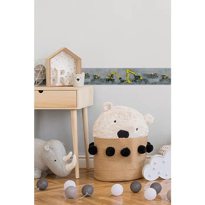 A.S. Création Only Borders 11 Tapetenborte Bagger - Kunststoff, Grau - Das Bild zeigt einen niedlichen Bärenkorb mit schwarzen Bommeln in einem Kinderzimmer, der als dekoratives und praktisches Element dient.