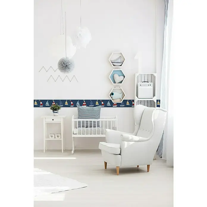 A.S. Création Lovely Kids Tapetenborte - Kunststoff, Segelschiffe - Ein charmantes Kinderzimmer mit einem weißen Sessel und einem Bordüre mit Segelbootmotiven, die eine maritime Atmosphäre schafft.