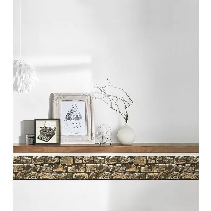 A.S. Création Only Borders 11 Tapetenborte Naturstein - 5 m x 17 cm x 5 cm, Kunststoff, Natursteinbraun - Eine stilvoll dekorierte Wand mit Holzregal, strukturierter Steinbasis und verschiedenen Ornamenten: gerahmte Kunst, Lampe, Ventilator und Vase.