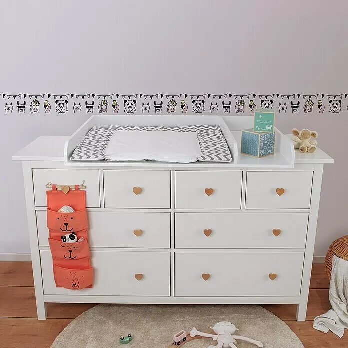 A.S. Création Lovely Kids Tapetenborte - Kunststoff, Fabeltiere - Weißer Wickeltisch mit grauer Chevron-Wickelauflage, orangefarbenem Stofforganizer und herzförmigen Holzknöpfen im Kinderzimmer.