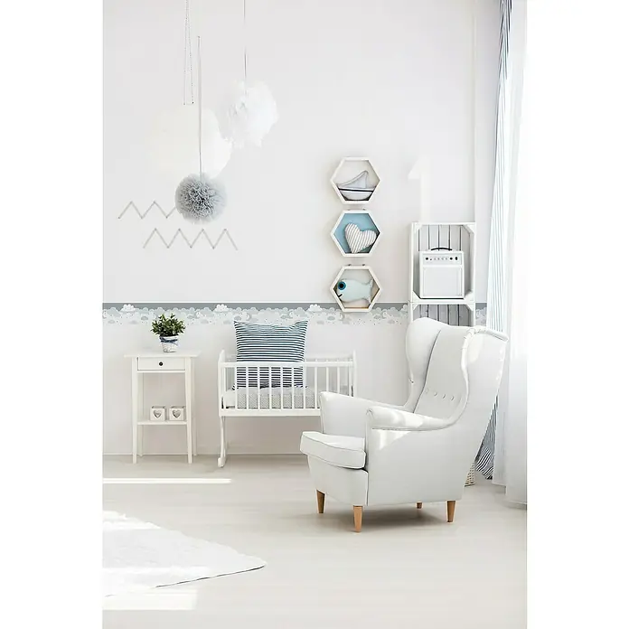 A.S. Création Only Borders 11 Tapetenborte Wolken - Kunststoff, Grau/Blau - Helles Kinderzimmer mit einem weißen Stillsessel, einem Kinderbett und verspielter Wanddekoration, die eine beruhigende Atmosphäre schafft.
