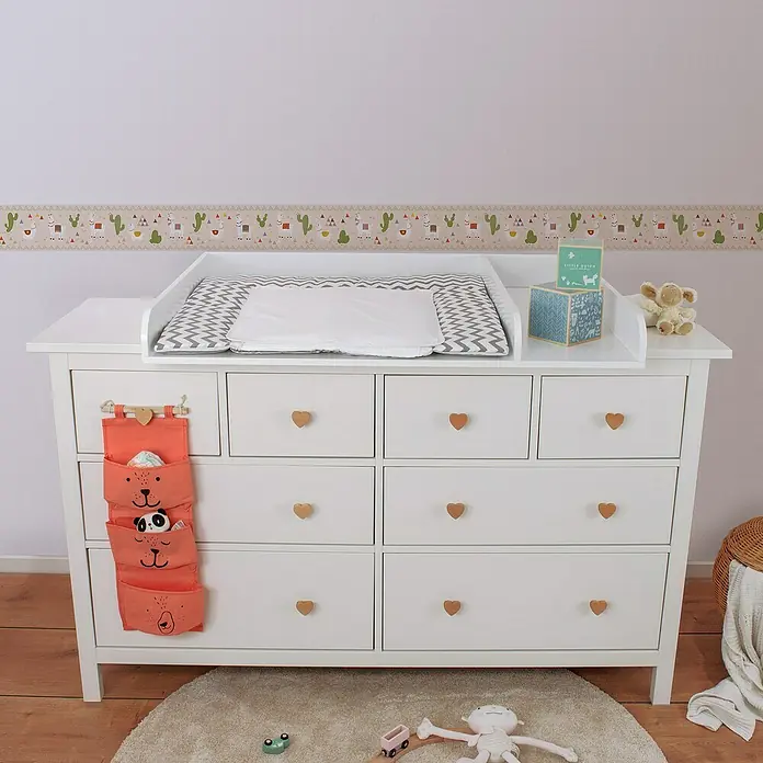 A.S. Création Lovely Kids Tapetenborte - Kunststoff, Wüste - Eine weiße Kommode mit Wickelaufsatz und herzförmigen Griffen, ideal für ein stilvolles und funktionales Kinderzimmer.
