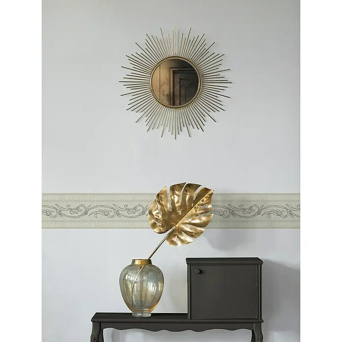 A.S. Création Only Borders 11 Tapetenborte Ranke - Cremebeige, 5 x 0,13 m, Selbstklebefolie - Ein goldenes Sonnenblumenspiegel hängt an der Wand über einem Tisch mit einem goldenen Blatt in einer Vase und einem dunklen Schrank.