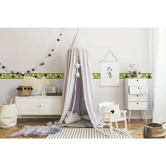 A.S. Création Lovely Kids Tapetenborte - Kunststoff, Schafe - Kinderzimmer mit Wickelkommode und Accessoires wie Spielzeug und einem Baldachin über einer Kindersitzgruppe.