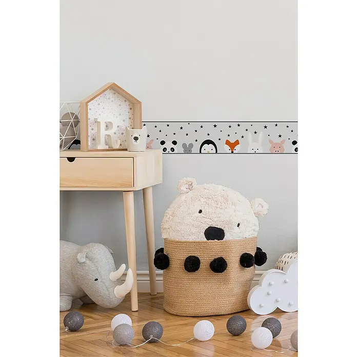 A.S. Création Lovely Kids Tapetenborte - Kunststoff, Tiere - Eine verspielte Kinderzimmerdekoration mit einer Tierbordüre und einem Bärenkorb für Spielzeug. Holzschreibtisch und Stofftier-Rhinozeros runden die Szene ab.