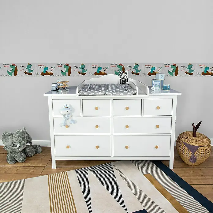 A.S. Création Lovely Kids Tapetenborte - Kunststoff, Dinos - Ein weißer Wickeltisch mit Schubladen und einer Dino-Bordüre an der Wand, ideal für ein stilvolles Kinderzimmer.
