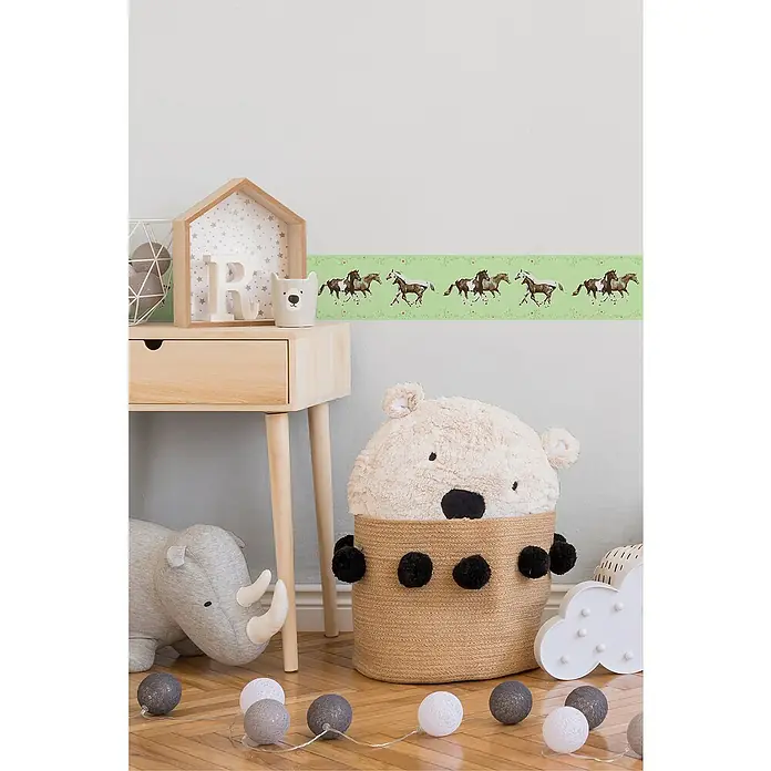 A.S. Création Only Borders 11 Tapetenborte Pferde - Kunststoff, Helgrün - Ein mit einem Teddybären gefüllter Korb ist Blickfang, daneben ein Holztisch und eine Deko-Lichterkette.