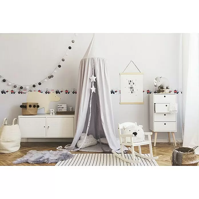 A.S. Création Lovely Kids Tapetenborte - Kunststoff, Monstertrucks - Ein hellgrauer Kinderbetthimmel mit weißen Sterndekorationen und Pompon-Besatz in einem Kinderzimmer.