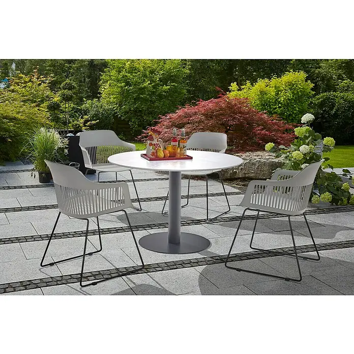 Gartenmöbel-Set Annika - 5 -tlg., Metall, Weiß/Schwarz/Flint Grey, Farbe Tischplatte: Hellgrau - Eine moderne Gartengarnitur mit grauem Tisch und Stühlen auf einer gepflasterten Terrasse mit üppigem Grün im Hintergrund.