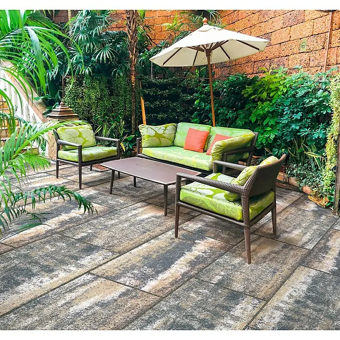 Terrassenplatte Saturn - 80 x 40 x 4 cm, Muschelkalk, Beton - Einladende Outdoor-Lounge-Gruppe mit grünen Polstern und einem Sonnenschirm auf einer gepflasterten Terrasse, ideal zum Entspannen im Freien.
