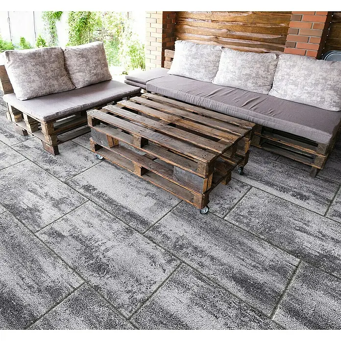 Terrassenplatte Saturn - 80 x 40 x 4 cm, Grau/Schwarz, Beton - Gemütliche Outdoor-Lounge-Möbel aus Paletten mit bequemen Kissen und einem Couchtisch aus Paletten auf einer Terrasse mit Steinplatten.