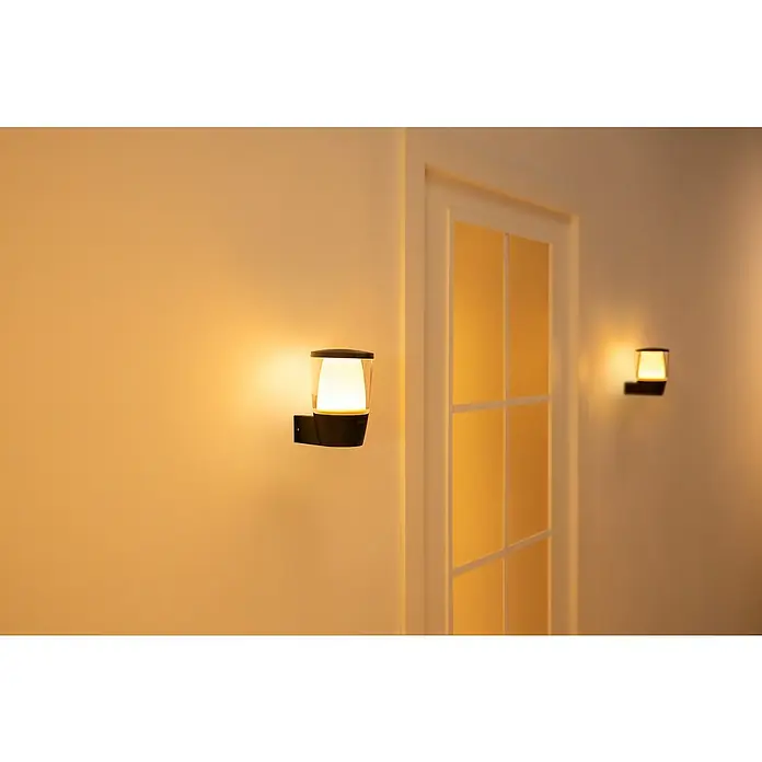 Philips Wiz LED-Außenwandleuchte Elpas - 8,5 W, 13,4 x 10,9 x 16,4 cm, IP44, RGBW - Moderne Wandleuchte mit warmem Lichtschein neben einer weißen Tür, die eine gemütliche Atmosphäre schafft.