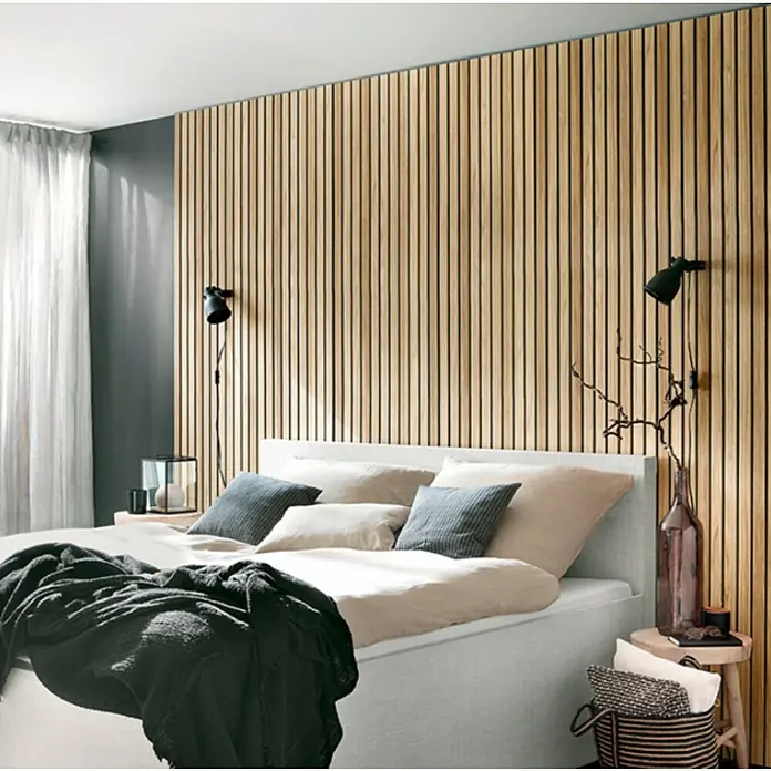 Panel de pared Linari - 120 x 50 cm, 2 ud. - Dormitorio con elegante pared de listones de madera, aportando calidez y estética natural a la habitación. La cama está decorada con cojines y una manta.