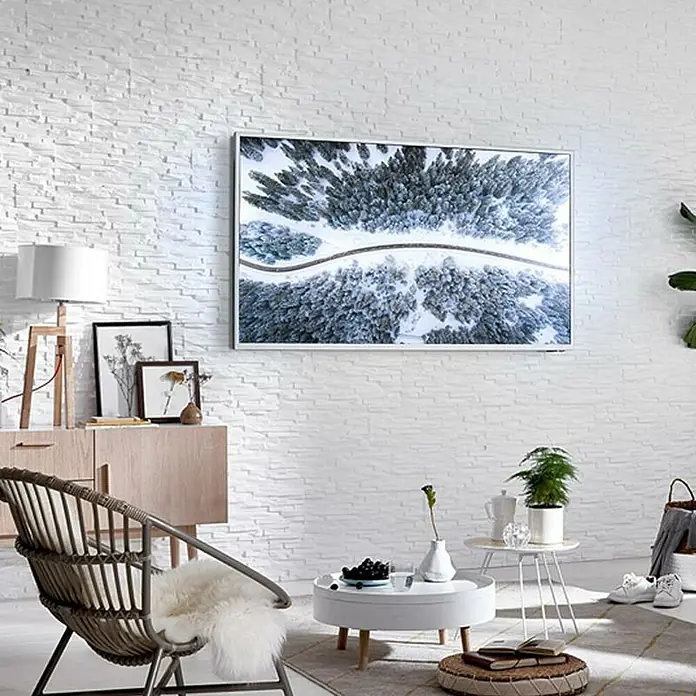 Panel de pared Benevento - 6 ud., 19 x 57 cm, Blanco - Primer plano de una sala de estar con un televisor en una pared de ladrillo que muestra un bosque nevado.