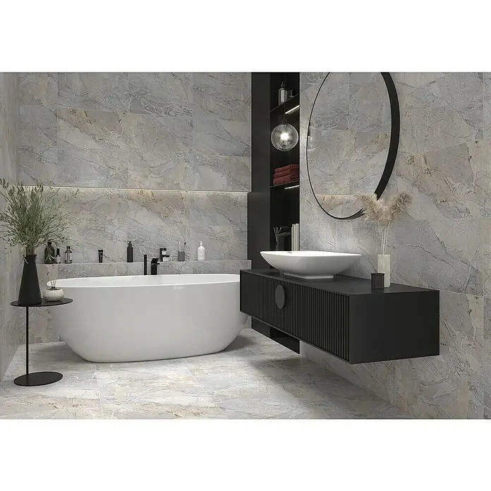 Feinsteinzeugfliese Side - 30 x 60 cm, Grau, Matt - Elegantes Badezimmer mit einer freistehenden Badewanne und einem stilvollen Waschtisch mit rundem Spiegel. Die grauen Marmorfliesen verleihen dem Raum eine luxuriöse Note.