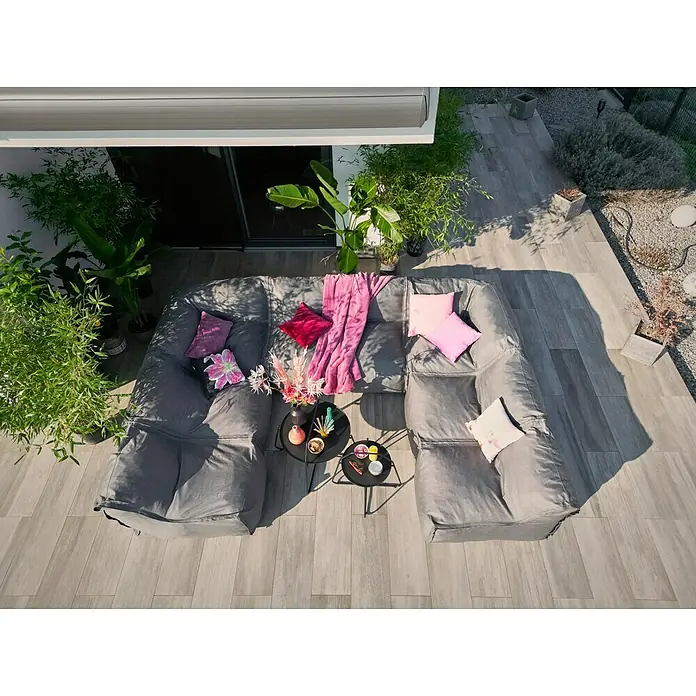 Loungesofa Modul - 107 x 107 x 72 cm, Polyesterfaser, Grau, Eckelement - Luftaufnahme eines grauen modularen Sitzbereichs mit Kissen und Tischchen, umgeben von üppigem Grün auf einer Terrasse.