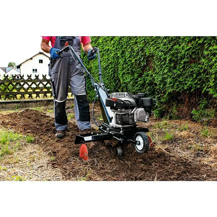 Scheppach Benzin-Bodenhacke MTP560 - 2.700 W, 4-Takt - Ein Mann benutzt eine Motorhacke, um den Garten umzugraben. Die Motorhacke lockert den Boden auf, während der Mann sie führt.