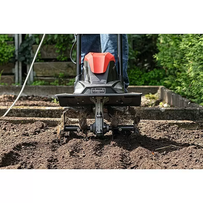 Scheppach Elektro-Bodenhacke MTE380 - Leistung: 1.050 W, Arbeitsbreite: 36 cm, Arbeitstiefe: 22 cm - Schwarze und rote Scheppach Gartenfräse bearbeitet braune Erde, von einer Person bedient.