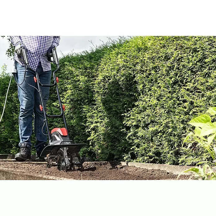 Scheppach Elektro-Bodenhacke MTE380 - Leistung: 1.050 W, Arbeitsbreite: 36 cm, Arbeitstiefe: 22 cm - Eine Person bearbeitet den Boden in einem Hochbeet mit einer rot-schwarzen elektrischen Gartenfräse.