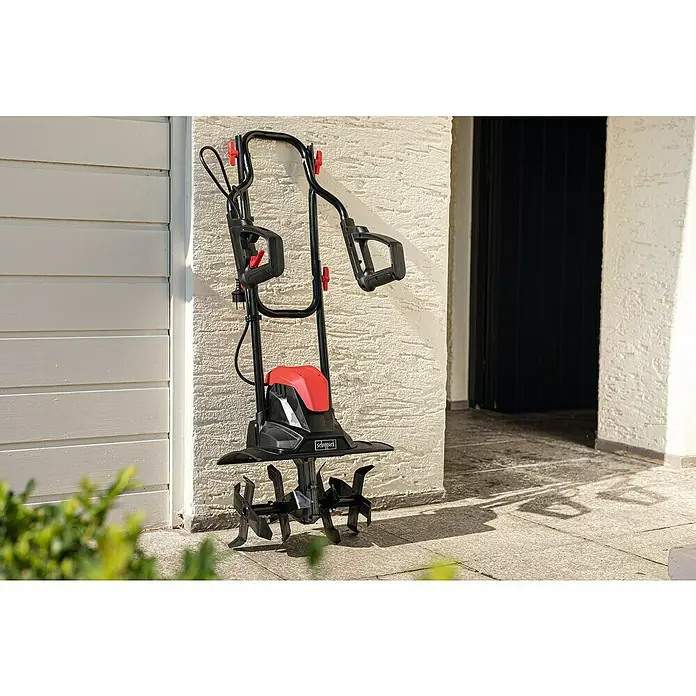 Scheppach Elektro-Bodenhacke MTE380 - Leistung: 1.050 W, Arbeitsbreite: 36 cm, Arbeitstiefe: 22 cm - Eine Scheppach Gartenfräse steht auf einer Terrasse vor einer Wand. Sie ist schwarz und rot und hat einen Griff zum Schieben.
