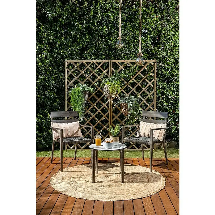 Silla de jardín Josefina - Bicolor gris, Apilable - Conjunto de muebles de exterior con dos sillas, una mesa y una alfombra sobre una terraza de madera frente a un seto verde. Ideal para relajarse al aire libre.