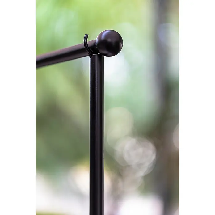 New Garden Guirnalda y barra decorativa Anuket - 9 W, 5 m, Amarillo, Marrón - Primer plano de un elegante perchero de metal negro mate con un extremo esférico, sobre un fondo verde borroso.