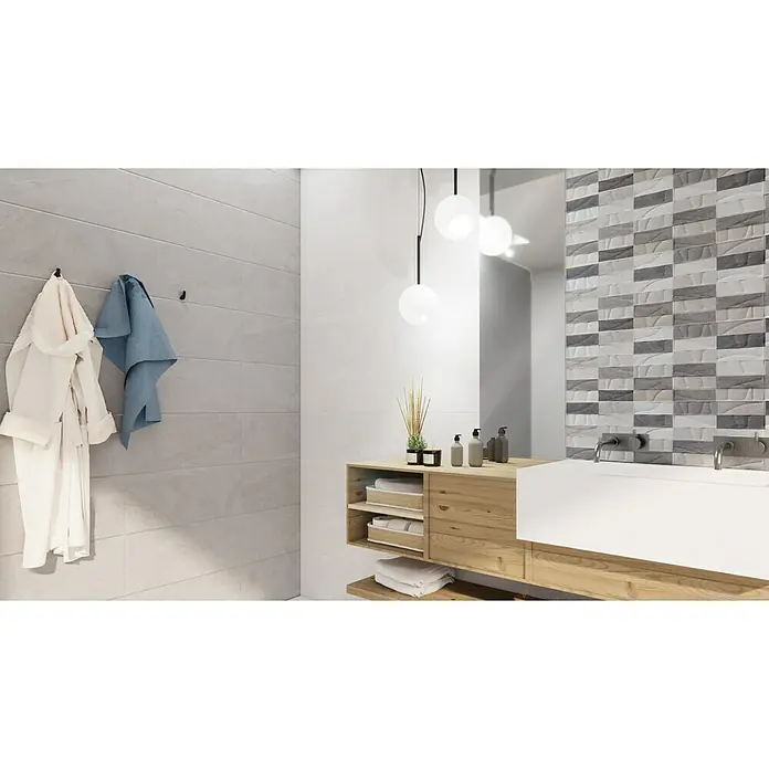 Revestimiento de pared Akane Mix - 30 x 90 cm, Gris/Blanco, Mate - Un baño con mueble de madera, lavabo sobre encimera blanco y azulejos decorativos en la pared. Toalla y albornoz colgados en la pared gris.