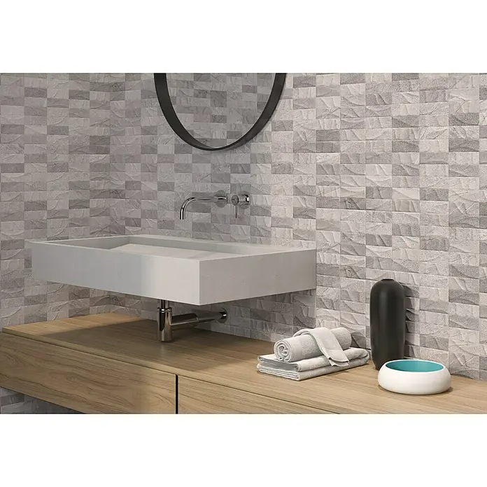 Revestimiento de pared Akane Mix - 30 x 90 cm, Gris/Blanco, Mate - Diseño de baño moderno con un elegante lavabo rectangular hecho de materiales de calidad y una pared de acento con azulejos grises texturizados.