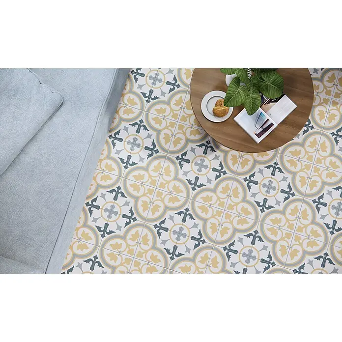 Pavimento porcelánico hidráulico Dover - 45 x 45 cm, Beige, Mate - Una vista desde arriba de un patrón de baldosas de cemento en tonos amarillo, gris y blanco, que añade un toque elegante a una habitación.