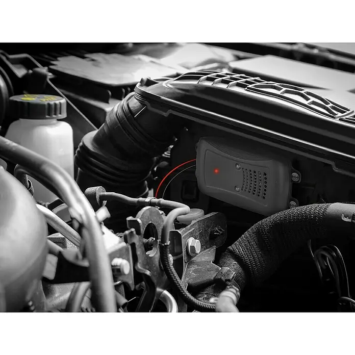 Marder Schreck Marderstop Kfz mit Blitz-LEDs - Schalldruckpegel: 95 dB - Nahaufnahme eines elektronischen Geräts im Motorraum eines Fahrzeugs, möglicherweise ein Steuergerät oder ein Sensor mit einer roten LED-Anzeige.