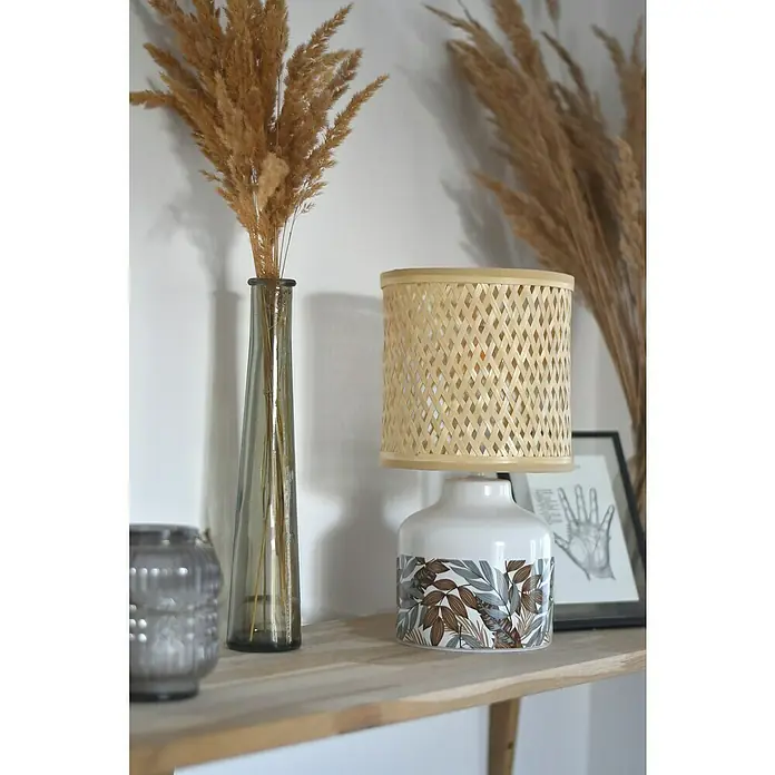 Idp Lampshades Lámpara de sobremesa Penny - 40 W, L x An x Al: 17 x 17 x 32 cm, Marrón, Natural, E14 - Una lámpara de mesa con pantalla de madera tejida está en una estantería de madera, junto a un jarrón delgado lleno de flores secas.