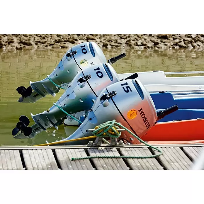 Honda Marine Außenbordmotor BF 10 SHU - 7,4 kW, Pinnensteuerung, Kurzschaft, Seilzug - Drei silberne Außenbordmotoren, zwei mit '10' und einer mit '15', an Booten an einem Holzsteg.