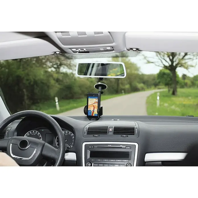 Hama Handyhalter Multi - 360 ° drehbar, Kunststoff, Schwarz, Geeignet für: Smartphones - Innenansicht eines Autos mit einem Smartphone-Halter an der Windschutzscheibe, der ein Navigations-App anzeigt, zur sicheren Navigation.