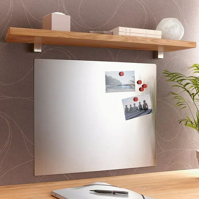 Mottez Protector de pared de cocina - Gris, 60 x 65 cm, Acero - Una estantería de pared de madera con una pizarra magnética debajo, que muestra fotos e imanes. Una planta de interior está a la derecha.