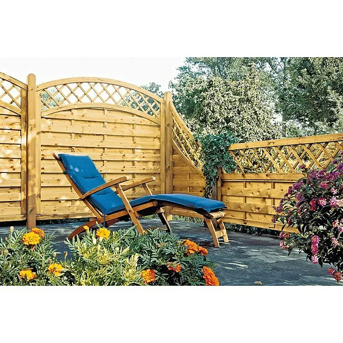 T & J Sichtschutzelement Avantgarde - 90 x 160/90 cm, Holz, Kesseldruckimprägniert Grün, Mit Doppelbogen - Entspannen Sie auf der blauen Gartenliege vor dem Holzzaun, umgeben von bunten Blumen, die eine gemütliche Atmosphäre schaffen.