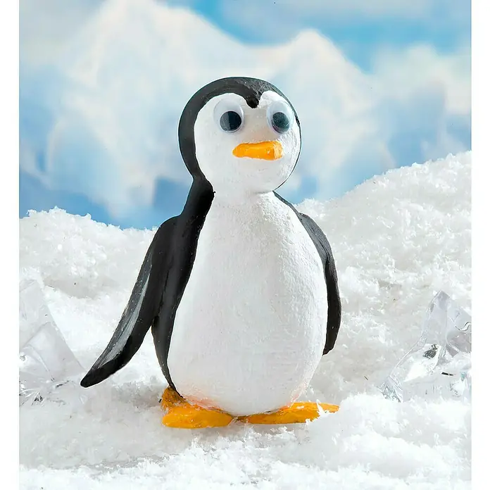 Glorex Gipsbinde Keratex - 2 m x 10 cm - Detailaufnahme eines niedlichen Pinguins aus Ton mit Knopfaugen, der auf einer Schneefläche vor einem verschwommenen Winterhimmel steht.