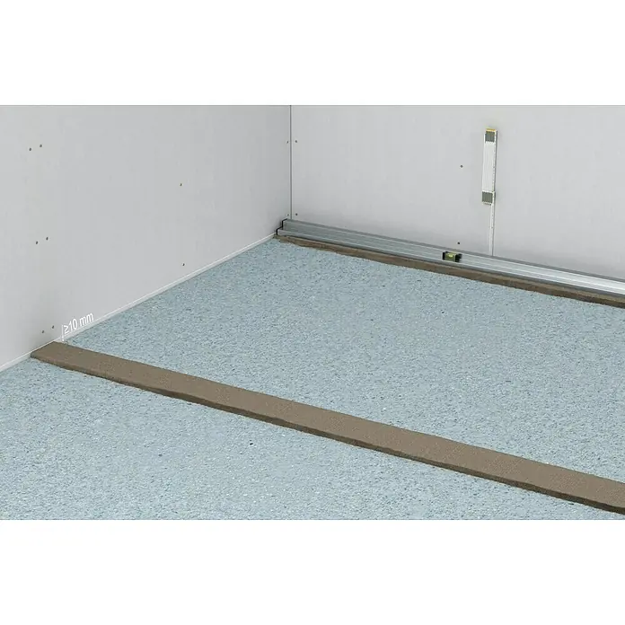 Fermacell Gebundene Schüttung - 80 l - Aufnahme eines Raumes mit blauem Bodenbelag und einer langen, silbernen Metallschiene an der Wand.