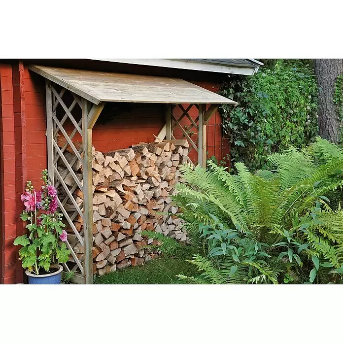 T & J Kaminholzregal Anne - 179 x 70 x 178 cm, Holz, Kesseldruckimprägniert grün - Hölzerner Brennholzunterstand an einem roten Gebäude, gefüllt mit gestapeltem Spaltholz.