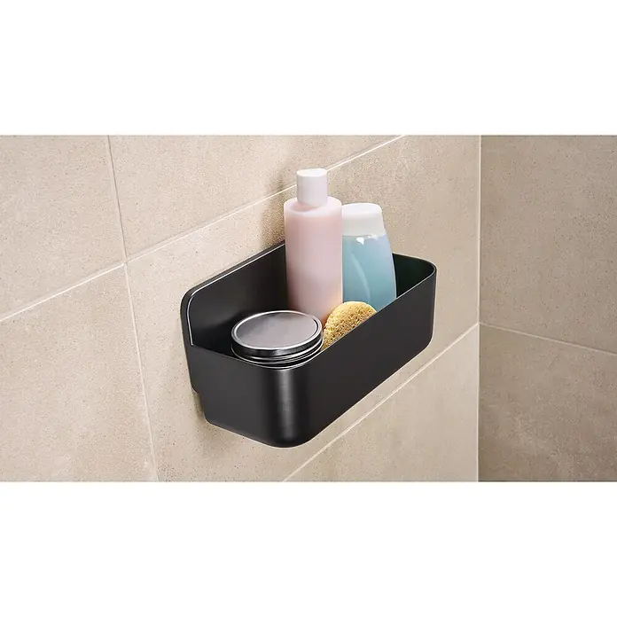 Tesa Cesta de baño Lavaa M - 26 x 11 x 13 cm, Plástico, Negro - Primer plano de una estantería negra de pared que contiene productos cosméticos, sujeta a una pared de azulejos. La estantería ofrece almacenaje.