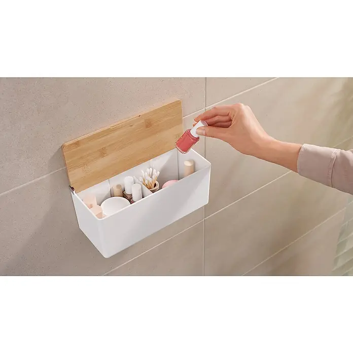 Tesa Caja de almacenaje Baboo M - L x An x Al: 24,2 x 10,2 x 11 cm, Plástico, Blanco y bambú - Un organizador de pared blanco con tapa de bambú se llena con varios artículos cosméticos, incluyendo esmalte de uñas, hisopos y cremas.