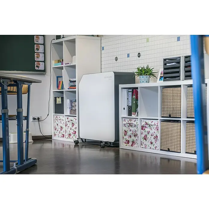 Hönle Luftreiniger SteriWhite Air Q60031,5 x 86 x 86 cm, Mit Standfuß, Max. Luftleistung: 600 m³/h - Das Bild zeigt einen "SternWhite Air" Luftreiniger in einem Klassenzimmer, platziert zwischen Regalen und einem Schreibtisch.