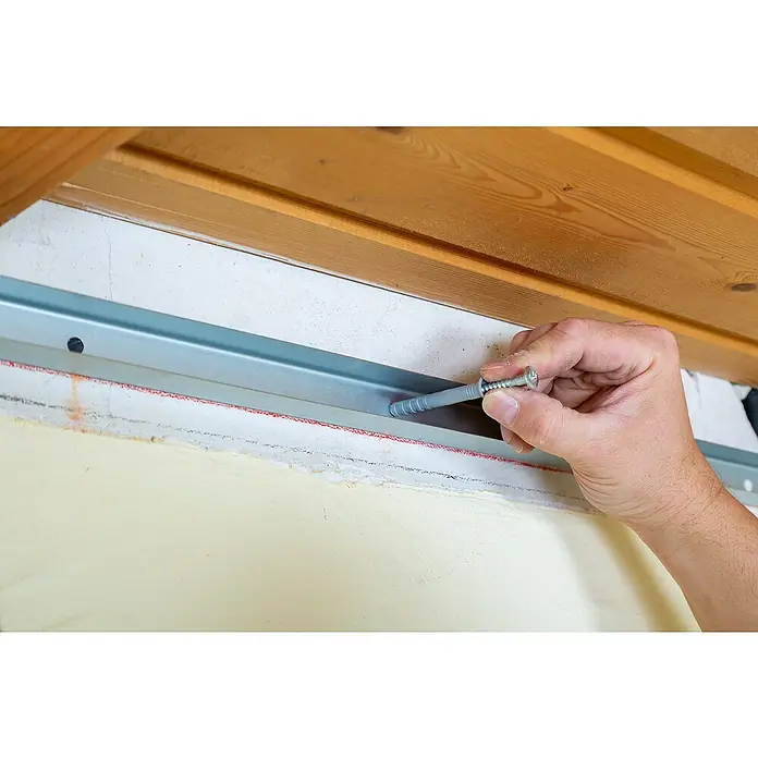 Knauf Drehstiftdübel K6/35 - Länge: 35 mm, 50 Stk. - Eine Hand, die eine Schraube in eine Dübelhülse an einer Metallschiene an einer Wand einführt.